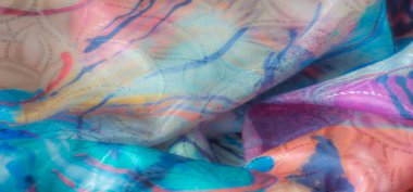 Hareketli, çok renkli, girdap desenli soyut bir kumaşın yakın çekimi. Dokular sıcak ve serin tonları harmanlayarak dinamik ve sanatsal bir tasarım yaratır..