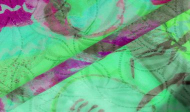 Yeşil ve morumsu renk şeması olan canlı, soyut bir kumaş. Kumaş dokulu, karmaşık desenler ve kıvrımlar sergiliyor, ışık altında parlak, yansıtıcı yüzeyler var..