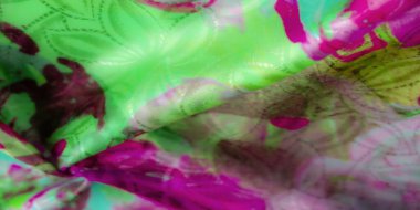 Katlanmış kumaş katmanları canlı yeşil ve pembe soyut çiçek desenleri sergiliyor. Katlar tekstil parlaklığını ve dokusunu vurgular..