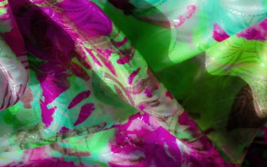 Pembe ve yeşilin canlı tonlarında akan bir kumaş. Soyut çizgiler ve ışığı yakalayan parıldayan bir yüzey..