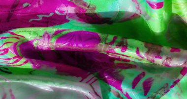 Canlı yeşil ve pembe bir kumaşa yakın plan detaylı desenler ve akış eğrileri, röfle ve yumuşak kıvrımlarla zenginleştirilip zengin bir doku oluşturuluyor..