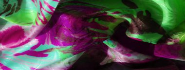 Canlı, pembe ve yeşil kumaşlı, parlak desenli, soyut desenleri ve ışık yansımalarını gösteren yakın plan çekimler..