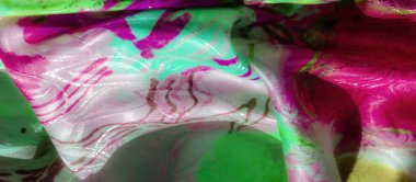 Yumuşak kıvrımlara sarılı soyut yeşil ve pembe kumaş. Karmaşık desenler ve parıldayan yansımalar, canlı ve dinamik bir görsel etki yaratıyor..