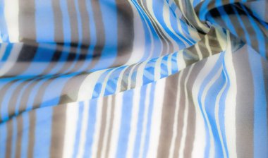 Kalın mavi, beyaz ve kahverengi çizgili, yumuşak ve dinamik bir dokuya sahip hafif bir kumaşın yakın çekimi..