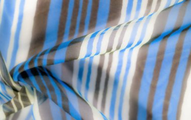 Mavi, beyaz ve kahverengi tonlarında çizgili kumaş, yumuşak ve narin bir dokuya sahip yumuşak katlama ve akış, modern ve sanatsal bir görünüm yaratır..