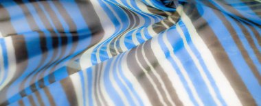 Kalın mavi, beyaz ve kahverengi çizgili, yumuşak ve dinamik bir dokuya sahip hafif bir kumaşın yakın çekimi..