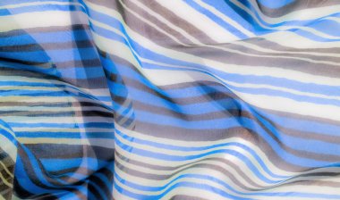 Dalgalı desenli, değişken mavi, kahverengi ve beyaz çizgili yumuşak, havadar bir kumaş, hafif ve zarif bir görsel efekt yaratır..