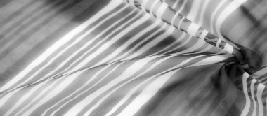 Kalın gri pullu çizgili bir kumaş dikey çalışıyor, dalgalı bir dokuya karışıyor ince bir eğim ve yumuşak hareket efektiyle..