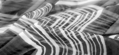 Dalgalı dikey çizgileri olan, sakin, modern, soyut bir tasarım yaratmak için yumuşak kıvrımlı ve akışkan gri bir kumaş..