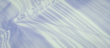 Pürüzsüz beyaz ve açık mavi çizgili kumaş akış ve yumuşaklık hissi yakalıyor..