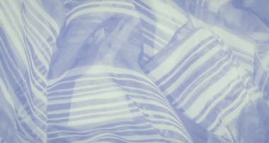 Yumuşak beyaz ve mavi çizgili kumaş, doğal kıvrımlarla ışık, huzur ve akışkan bir tasarım yaratıyor.