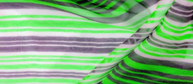 Görüntüler serisi hafif kumaş üzerinde canlı yeşil ve gri yatay çizgiler içererek, görsel olarak dinamik ve akışkan bir model oluşturur. Dalgalı çizgiler, açık ve koyu tonların karışımını sunar..