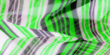 Yumuşak kıvrımlı, yeşil, beyaz ve gri çizgili dinamik bir kumaş çekimi. Kumaş nazikçe kıvrılır, renk ve ışığın etkileşimini ortaya çıkarır.