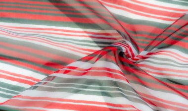 Canlı ve dinamik kırmızı, beyaz ve yeşil çizgili kumaş zarif kumaşlı. Sarmaş dolaş kıvrımlar hareket ve akıcılık hissi yaratıyor, renk farklılıklarını vurguluyor..