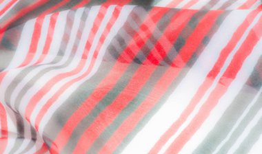 Canlı kırmızı, yeşil ve beyaz çizgileri zarif kıvrımlarla örtülmüş bir kumaş. Yakından çekilen görüntü, materyalin karmaşık detaylarını yakalar ve pürüzsüz, akıcı dokusunu vurgular.