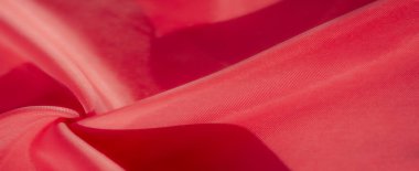 Kırmızı kumaştan çarpıcı bir yakın çekim, pürüzsüz dokusunu ve narin kıvrımlarını yakalıyor. Parlak kırmızı renk ve ince parıltı lüks ve zarif bir his yaratır..