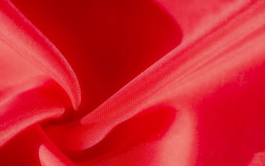 Zarif dokumasını ve canlı rengini gösteren kırmızı bir kumaşın çarpıcı yakın çekimi. Kumaş nazikçe katlanır, hem yumuşaklık hem de sıcaklığı çağrıştıran zengin, dokunsal bir doku sunar..