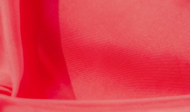 Karmaşık dokuları olan canlı kırmızı kumaşın yakın çekim görüntüsü. Katlar ve ışıklandırma yumuşak, akışkan bir görünüm yaratır. Malzemenin ince dokusunu ve zengin, derin rengini vurgular..