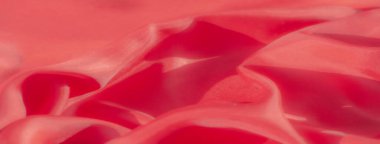 Bu yakın plan fotoğraf canlı kırmızı bir tekstilin narin örtüsünü yakalıyor, ipeksi dokusunu ve organik kıvrımlarını vurguluyor. Düz yüzey ışığı yansıtır ve kumaşın görünümüne derinlik katar..