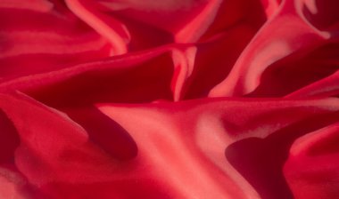 Lüks kırmızı bir kumaş, yakın plan çekilmiş, yumuşak, akışkan kıvrımlarını ve hassas kıvrımlarını gösteriyor. Materyalin dokusu ve ayrıntısı ışık oyunuyla geliştirilir.