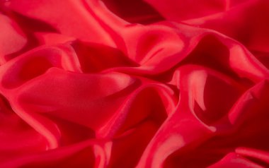 Koyu kırmızı kumaşın zengin dokusunu ve karmaşık kıvrımlarını gösteren yakın plan bir çekim. Maddenin hassas, akışkan doğası canlı rengiyle gelişir.,