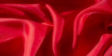 Bu görüntü, pürüzsüz dokusunu ve ince ışık yansımalarını gösteren canlı kırmızı bir kumaşı yakından gösteriyor. Katlar akışkan, zarif bir hareket yaratıyor, zengin renkleri vurguluyor.