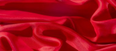 Yumuşak, akışkan kıvrımlı kırmızı kumaştan soyut bir yakın çekim. Dokulu yüzeydeki ışık oyunu dinamik ama yatıştırıcı bir görsel yaratıyor. Zengin renk görüntüye derinlik ve enerji katar.