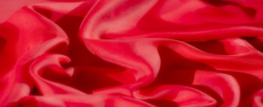 Kırmızı kumaşlı, ipek kumaşlı ve zarif kıvrımlı bir makro çekim. Yumuşak, akışkan madde ışığı çok güzel yakalıyor, lüks ve stili çağrıştıran soyut desenler oluşturuyor..