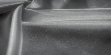 Yumuşak bir monokrom palette yakalanmış, zengin kıvrımlı kumaşın zarif bir sunumu. Işık ve gölge yüzeyde oynayarak maddenin karmaşık dokusunu geliştirir..