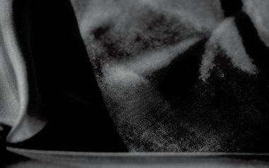 Kumaşın soyut yakın çekimi, sıvı kıvrımlarını ve tek renkli dokusunu gösteriyor. Yumuşak, pürüzsüz kumaş doğal olarak ışık ve gölgenin etkisiyle derinlik katar..