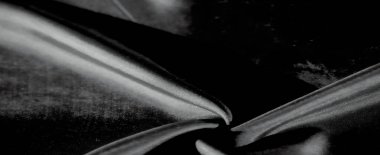 Yumuşak gri renkte kumaşın akıcı ve soyut bir görüntüsü. Pürüzsüz madde nazikçe kıvrılır ve ışık narin dokuyu hafifçe aydınlatırken sakin bir görsel efekt yaratır..