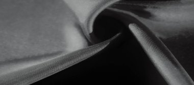 Kumaşın yumuşak kıvrımları nazikçe aydınlatılır ve ışık ve gölgenin sanatsal etkileşimini yaratır. Materyalin pürüzsüz dokusu tek renkli tonları ile gelişir ve sakin bir görsel sunar..
