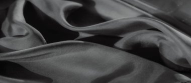 Bu siyah ve beyaz yakın plan görüntü pürüzsüz, akışkan kumaş kıvrımları sergiliyor, röfleler ve gölgeler bir doku ve derinlik hissi yaratıyor. Kumaş ipeksi ve yumuşak görünüyor.,
