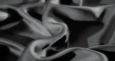 Bu siyah ve beyaz yakın plan görüntü pürüzsüz, akışkan kumaş kıvrımları sergiliyor, röfleler ve gölgeler bir doku ve derinlik hissi yaratıyor. Kumaş ipeksi ve yumuşak görünüyor.,