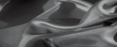 Yumuşak kırışık kumaştan siyah beyaz bir yakın çekim. Işığın ve gölgenin etkileşimi derinlik yaratır, kumaşın zarif örtüsünü vurgular, moda veya iç tasarım için ideal hale getirir..