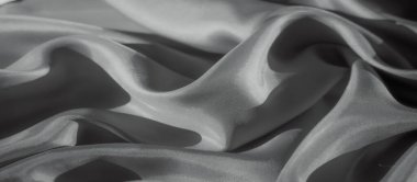 Zarif bir şekilde örtülmüş, yumuşak dokusunu gözler önüne seren büyüleyici bir ipek kumaş. Yumuşak kıvrımlar ve narin ışıklandırma bir hareket, lüks ve incelikli basitlik hissi yaratır..