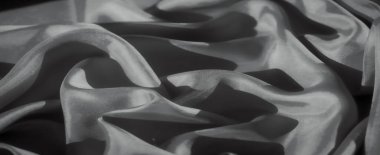 Yumuşak kumaş kıvrımları, hafif kıvrımlar ve gölge oyunlarıyla soyut bir çekim. Kumaşın pürüzsüz yüzeyi karanlık alanlara karşı tezat oluşturarak zarif ve sofistike bir doku tasarımı oluşturur..