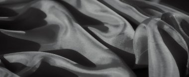 Zarif kumaş kıvrımlarını ve yumuşak gölgeleri gösteren, zarif arkaplan ve tasarım projeleri için mükemmel, sakin ve soyut bir doku yaratan sofistike gri tonlu bir resim..