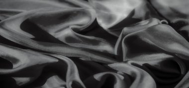 Gri tonda zarif, akıcı kumaşın yakın plan çekimi pürüzsüz kıvrımlar ve ince dokular sergiliyor. Işık ve gölgeler, maddenin dokuma ve akışının karmaşık detaylarını güçlendirir..