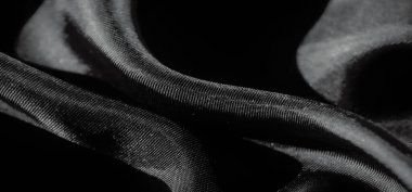 Zarif kıvrımları ve pürüzsüz, lüks bir yüzeyi olan gri tonda çekilmiş akıcı bir kumaş dokusu. Gölgeler ve gölgeler, yumuşak ve soyut bir kompozisyon oluşturmak için etkileşim halindeler..