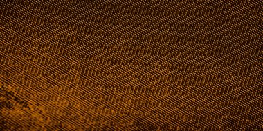 Sıcak kahverengi ve turuncu tonlarda desenli dokulu bir yüzeye yakın çekim. Bu ipek, küçük dairelerden oluşan ince bir şebeke, organik gibi hissettiren karmaşık bir dizayn yaratıyor..