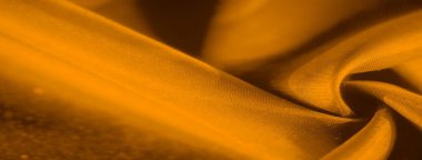 Pürüzsüz altın kumaş ışığı çok güzel yansıtıyor. Yumuşaklık hissi veren narin kıvrımları var. Işık ve gölgenin etkileşimi derinlik ve boyut hissi katar..