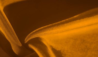 Çekici kıvrımlar ve zengin bir doku yaratan yumuşak, altın kumaşın yakından görünüşü. Gölge ve ışığın etkileşimi bu lüks tekstil bileşimine derinlik ve sıcaklık ekler..