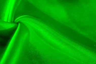 Canlı yeşil kumaş kıvrımları, sergilenen doku, derinlik ve ışık yansıması içeren karmaşık bir görüntü. Soyut ve organik eğriler, arka plan ve markalaşma için uygun hale getiriyor.