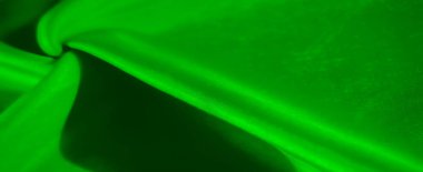 Karmaşık dokular ve ışık desenleri yaratan kıvrımlı ve katlı yeşil kumaşlar. Zengin zümrüt tonu ve kumaşın ipeksi parıltısı lüks ve yumuşak bir izlenim yaratır..