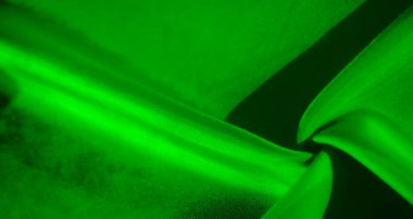 Bu kumaş görüntüde yumuşak kıvrımlı yeşil kumaş minimalist bir görünüm sergiliyor, ışığın maddenin ince dokusunu ve parlak görünümünü geliştirdiği, ince bir dokunuş verdiği yerde.