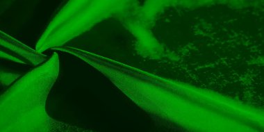 Görüntü hareket halindeki yeşil kumaşın yakın çekimini vurgular, bükülürken ve bükülürken ipeksi pürüzsüzlüğünü yakalar, soyut ama dinamik bir görsel izlenim yaratır..