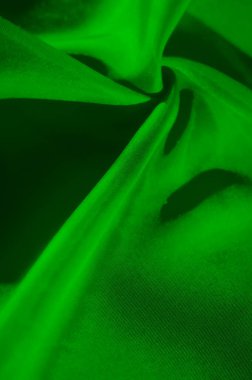 Görsel olarak çekici, soyut bir estetik yaratan yumuşak ışıklandırmayla geliştirilmiş zarif kıvrımlar ve parlak dokular sergilenen akışkan yeşil bir kumaşın sanatsal çekimi..