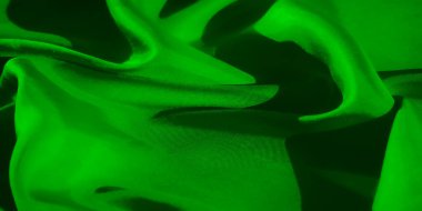 Narin kıvrımları ve pürüzsüz dokuları olan yeşil kumaşın makro görüntüsü ışık ve gölgenin zarif etkileşimini sergiliyor. Görüntü soyut ve sanatsal bir his yayar..