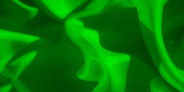 Yumuşak kıvrımlı pürüzsüz yeşil bir kumaş. Canlı yeşil renk ve doku, ışığın ve gölgenin görsel olarak çekici bir kontrastı oluşturarak, maddenin ipeksi yüzeyini vurguluyor..